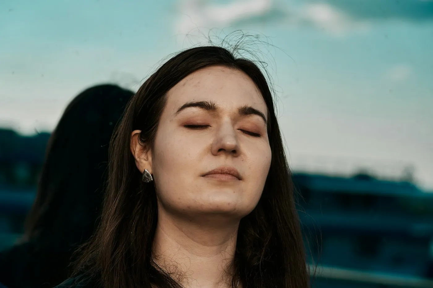 Woman with her eyes closed breathing slowly outdoors to calm a panic attack