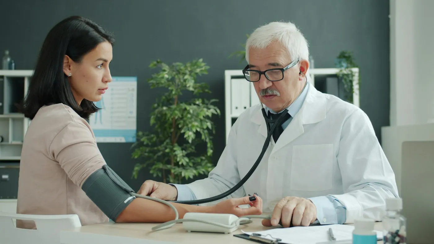 Doctor checking a young woman's blood pressure during a calm clinic appointment