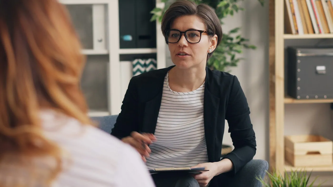 Therapist in glasses explaining an idea to a client during a cognitive behavioral therapy session