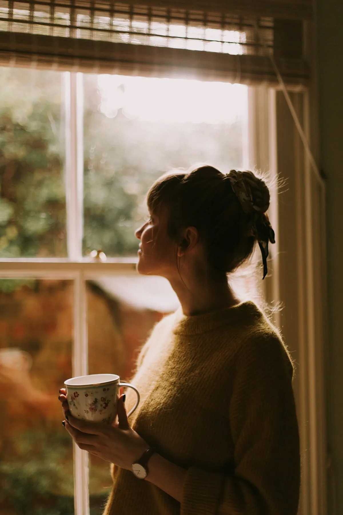 Woman enjoying a quiet, mindful moment with tea by a sunny window